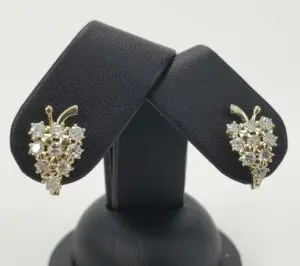 Gold grape cluster earrings on black stand.
