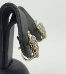 Gold earrings with diamonds on display stand.