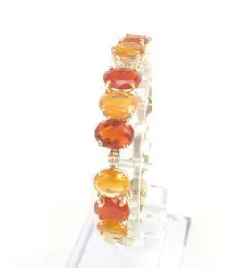 Gold bracelet with red and orange stones.