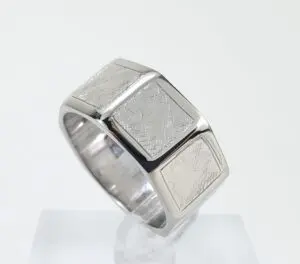 Silver geometric-patterned ring on display stand.