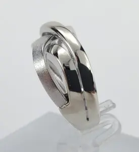 Silver intertwined rings on a clear stand.