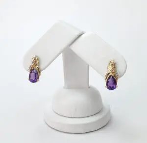 Gold earrings with purple teardrop gemstones.
