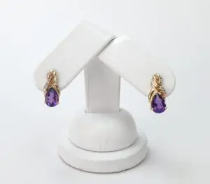 Gold earrings with purple teardrop gemstones.