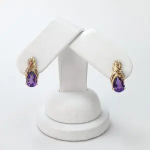 Gold earrings with purple teardrop gemstones.