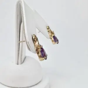 Gold earrings with purple gemstones displayed upright.