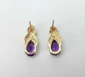 Gold earrings with purple gemstones.