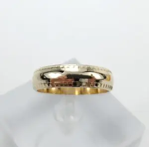 Gold ring with engraved pattern on stand.