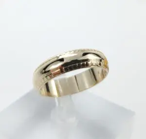 Gold ring with engraved patterns displayed.
