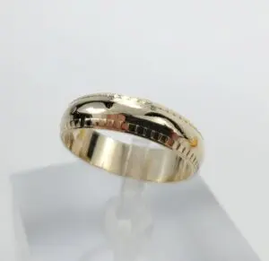 Gold ring with engraved pattern on display.