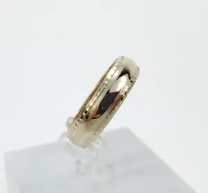 Gold ring with engraved edges on display.