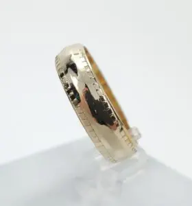 Gold ring with textured edges on display.
