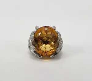 Large yellow gemstone ring with ornate setting.