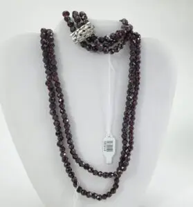 Dark beaded necklace on display stand.