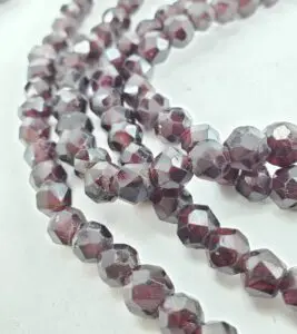 Faceted garnet gemstone strands on display.