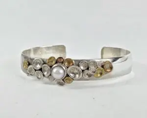 Silver bracelet with pearl and metal accents.