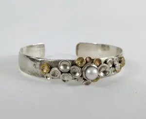 Silver bracelet with pearl and circular accents.