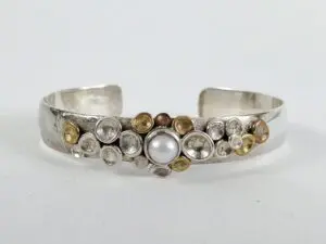 Silver bracelet with pearl and circular accents.