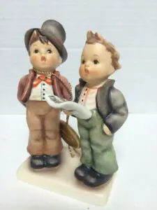 Two figurines of young boys singing.