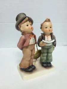 Two ceramic figurines of children standing together.