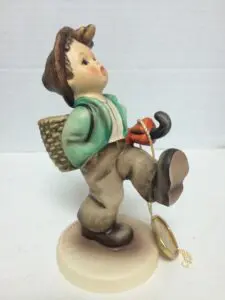 Child figurine walking with backpack and umbrella.