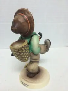 Ceramic figurine of a boy with basket.