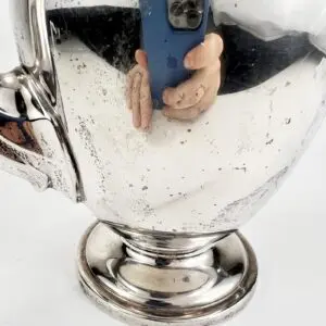 Reflection in a polished silver teapot surface.