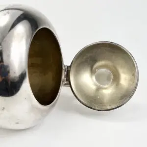 Silver teapot with open lid.
