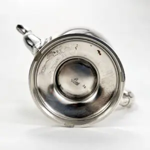 Bottom view of a silver teapot.