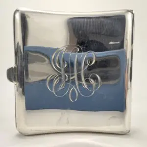Silver flask with engraved initials on front.