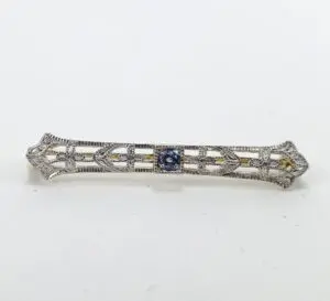 Ornate silver bar brooch with blue stone.