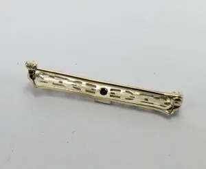 Gold bar brooch with intricate design.