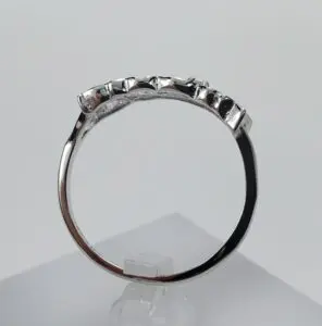 Silver ring with gemstones on display stand.