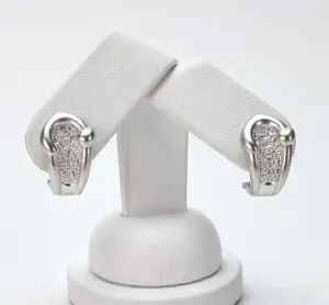 Silver earrings on a white display stand.