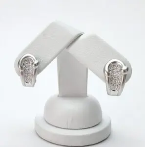 Silver earrings with textured design on stand.