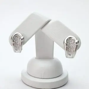 Silver earrings with textured design on stand.