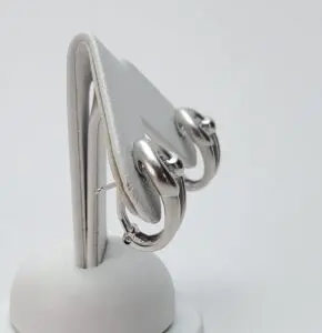 Silver hoop earrings on display stand.