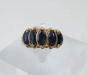 Gold ring with five dark gemstones.