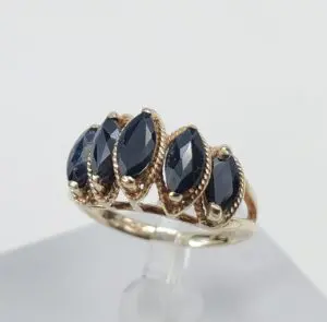 Gold ring with four dark gemstones.