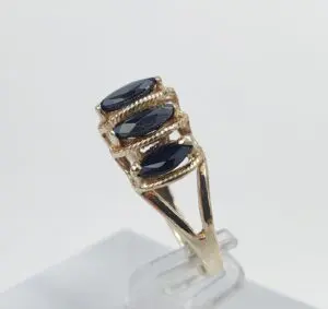 Gold ring with three dark gemstones.