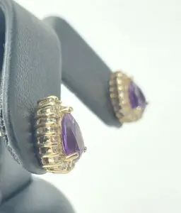 Gold earrings with purple gemstones on display.