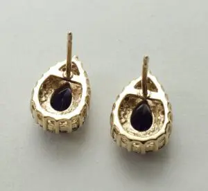 Gold teardrop earrings with dark gemstones.