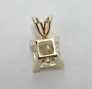 Gold pendant with a square gemstone.