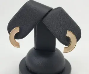 Gold crescent earrings on black display stand.