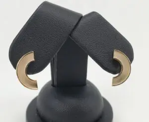 Gold crescent-shaped earrings on black stand.