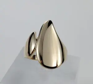 Gold abstract-shaped ring on display stand.