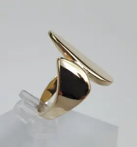 Gold abstract ring on clear stand.