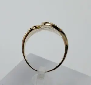 Gold ring on white display stand.