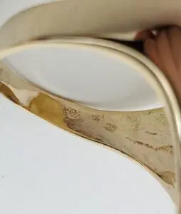 Gold bracelet with engraved hallmarks and hand.