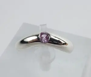 Silver ring with purple gemstone on display.