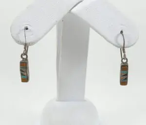 Colorful dangle earrings on white display stand.